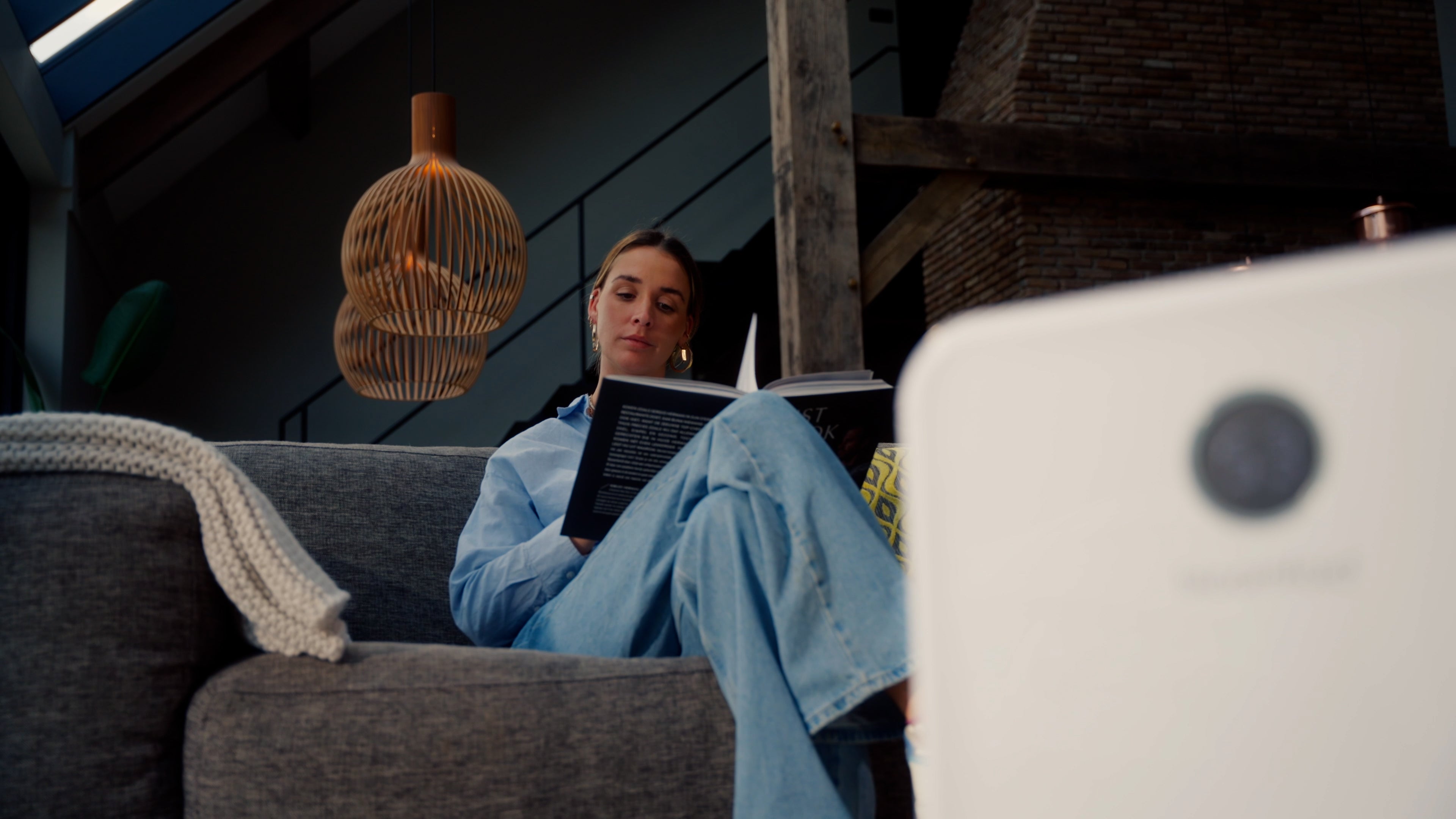 Vrouw leest boek op de bank met Bloomfold luchtreiniger op de voorgrond